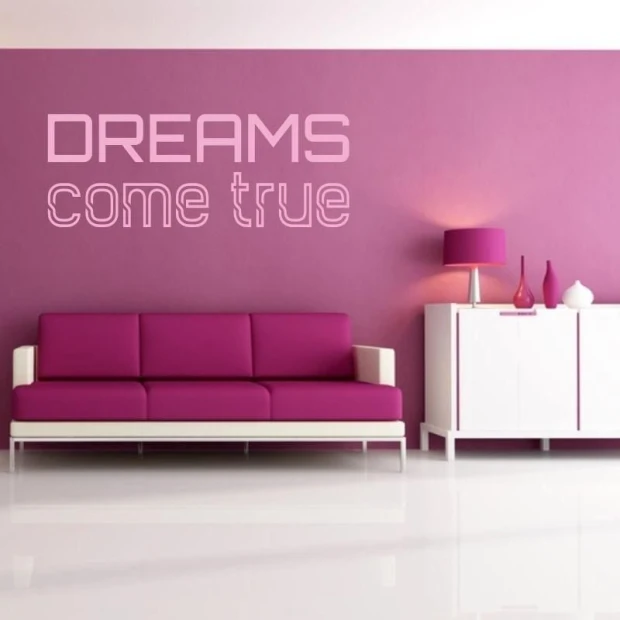 Naklejka ścienna z napisem "DREAMS come true" w przykładowym różowym kolorze, naklejona na ścianie