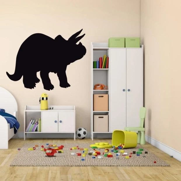 Naklejka kredowa w kształcie dinozaura triceratopsa naklejona na ścianie we wnętrzu pokoju dziecięcego