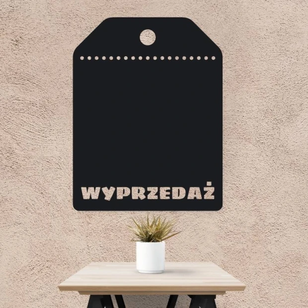 Naklejka kredowa w kształcie metki z wyciętym napisem WYPRZEDAŻ i otworami, naklejona na ścianę