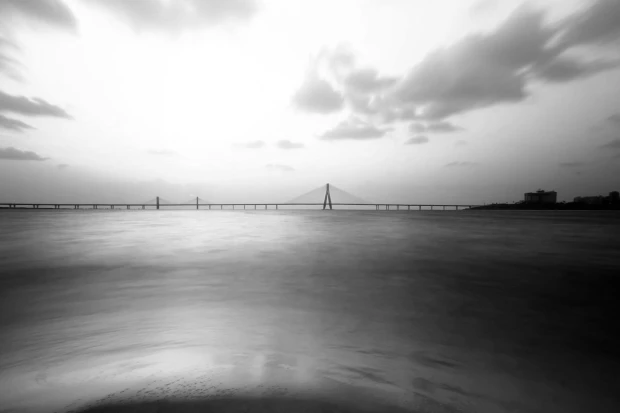 Fototapeta z czarno-białym nadrukiem długiego mostu nad wodą, przedstawiona jako wzór na białym tle