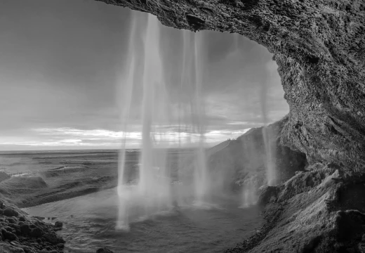 Fototapeta na ścianę z czarno-białym nadrukiem wodospadu Seljalandsfoss w Islandii widocznego z wnętrza jaskini