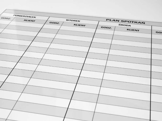 Tablica magnetyczna suchościeralna z przykładowym nadrukiem planu spotkań w ujęciu pokazującym detal tabeli