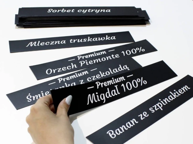 MAGNES z powierzchnią kredową oraz nadrukiem na wymiar - Wzór graficzny. Czarny prostokąt z białym tekstem, różne napisy
