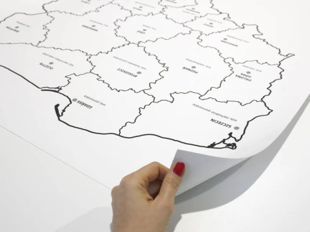 Tablica suchościeralna z nadrukiem mapy Polski w ujęciu pokazującym odklejanie narożnika folii samoprzylepnej