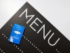 Tablica kredowa z nadrukiem menu 021 - Wzór graficzny. Na czarnym tle białe litery tworzą napis MENU oraz białe kropki