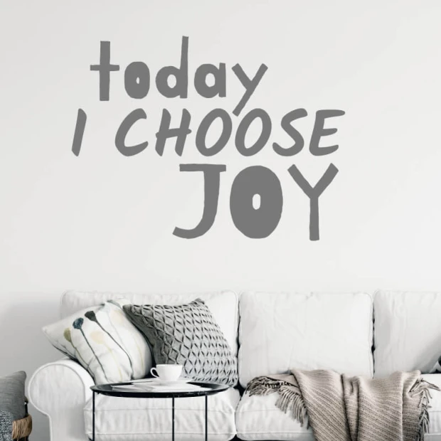 Szablon malarski z napisem Today I choose joy w przykładowej szarej kolorystyce na ścianie nad sofą