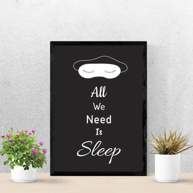 Czarny plakat w ciemnej ramie z białym napisem All We Need Is Sleep oraz grafiką opaski na oczy do spania