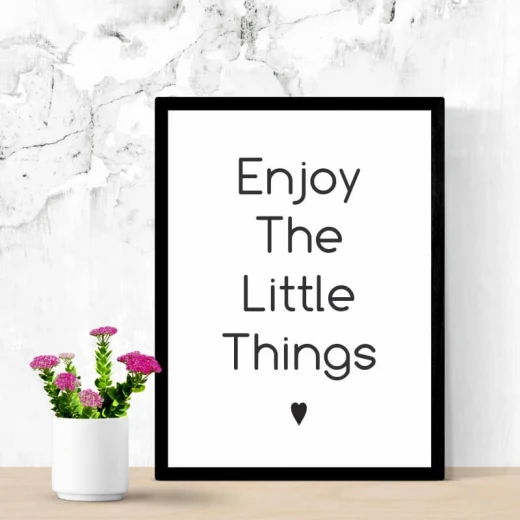 Plakat w czarnej ramie z minimalistycznym napisem Enjoy The Little Things i małym serduszkiem na białym tle