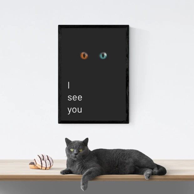 Plakat w czarnej ramie z napisem I see you oraz motywem świecących kocich oczu na ciemnym tle