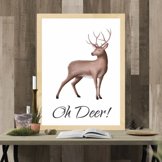Plakat z nadrukiem jelenia i napisem Oh Deer oprawiony w jasną drewnianą ramę zaprezentowany we wnętrzu
