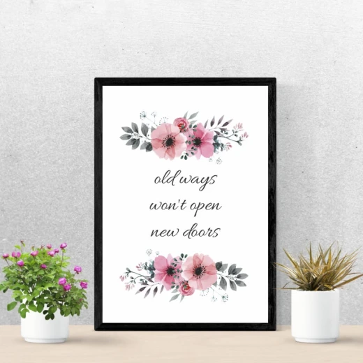 Plakat w czarnej ramie z angielskim cytatem Old ways won\'t open new doors oraz motywem różowych kwiatów