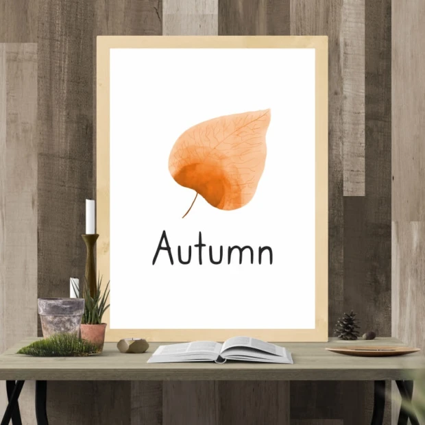 Plakat z nadrukiem pomarańczowego liścia i napisem Autumn, oprawiony w jasną, drewnianą ramę