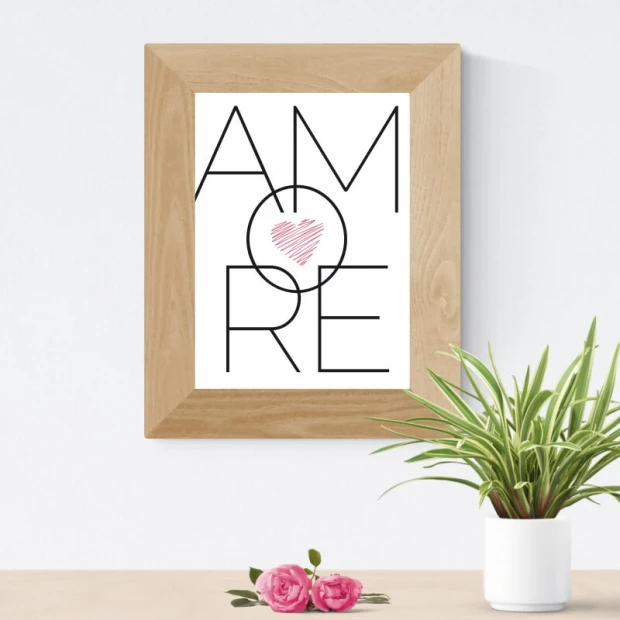 Plakat typograficzny z napisem AMORE i różowym sercem, zaprezentowany w jasnej drewnianej ramie