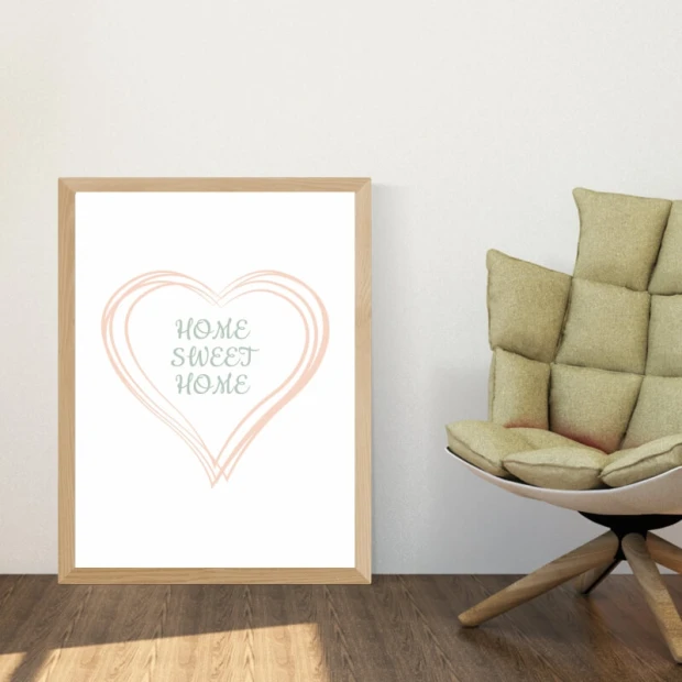 Plakat w jasnej drewnianej ramie z napisem Home sweet home wpisanym w różowe serce we wnętrzu