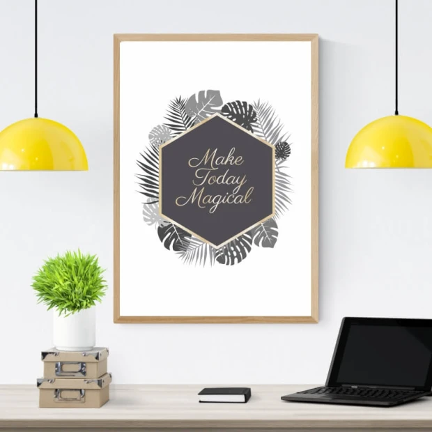 Plakat w jasnej drewnianej ramie z angielskim napisem Make today magical w otoczeniu tropikalnych liści