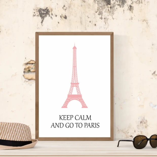 Plakat w brązowej ramie z różową Wieżą Eiffla oraz czarnym napisem Keep calm and go to Paris na białym tle