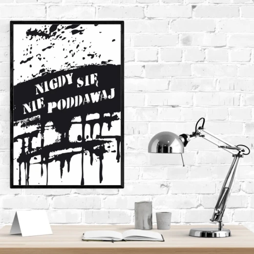 Plakat w czarnej ramie z motywacyjnym napisem Nigdy się nie poddawaj na tle czarnych plam i zacieków
