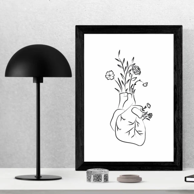 Plakat z czarno-białym nadrukiem anatomicznego serca z wyrastającymi kwiatami, oprawiony w czarną ramę