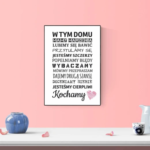 Plakat w czarnej ramie z polskim napisem W tym domu i różowym sercem zaprezentowany we wnętrzu