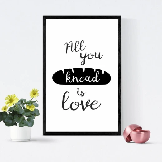 Plakat do kuchni z czarnym napisem All you knead is love i grafiką chleba, oprawiony w czarną ramę