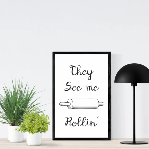 Plakat do kuchni w czarnej ramie z napisem They see me rollin i grafiką wałka do ciasta