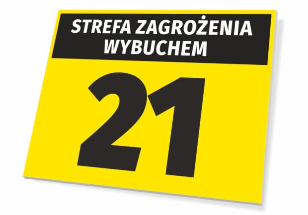 Żółta tabliczka BHP z czarnym napisem STREFA ZAGROŻENIA WYBUCHEM oraz dużą cyfrą 21 na białym tle
