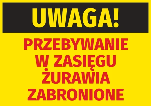 Żółta naklejka ostrzegawcza BHP z napisem Uwaga Przebywanie w zasięgu żurawia zabronione na plac budowy