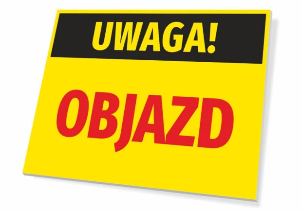 Żółta ostrzegawcza tabliczka z czarnym pasem i napisem UWAGA! OBJAZD na białym tle