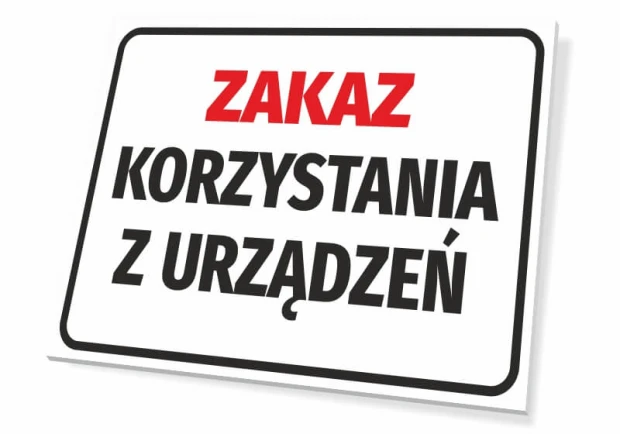 Tabliczka BHP z czerwono-czarnym napisem ZAKAZ KORZYSTANIA Z URZĄDZEŃ na białym tle, pokazana pod kątem
