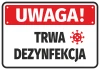 Naklejka Uwaga Trwa dezynfekcja - Wzór graficzny. Czerwone tło z białym napisem i symbolem wirusa