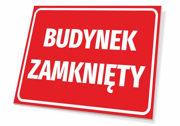 Czerwona prostokątna tabliczka informacyjna BHP z białym napisem BUDYNEK ZAMKNIĘTY i ramką, widok pod kątem
