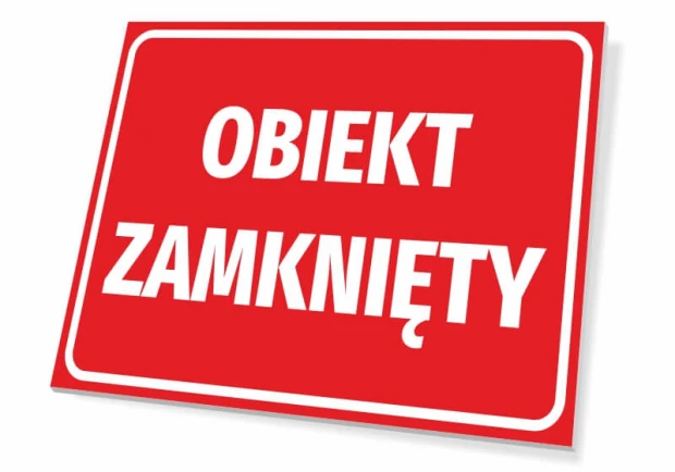 Czerwona prostokątna tabliczka informacyjna z białym napisem Obiekt zamknięty w ujęciu pokazującym jej grubość