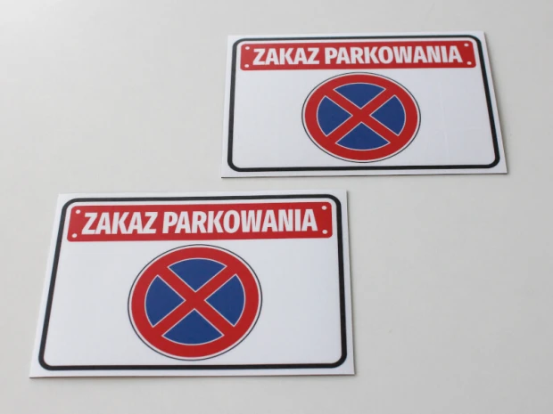 Dwie naklejki na garaż z czerwonym napisem ZAKAZ PARKOWANIA i niebiesko-czerwonym znakiem zakazu zatrzymywania
