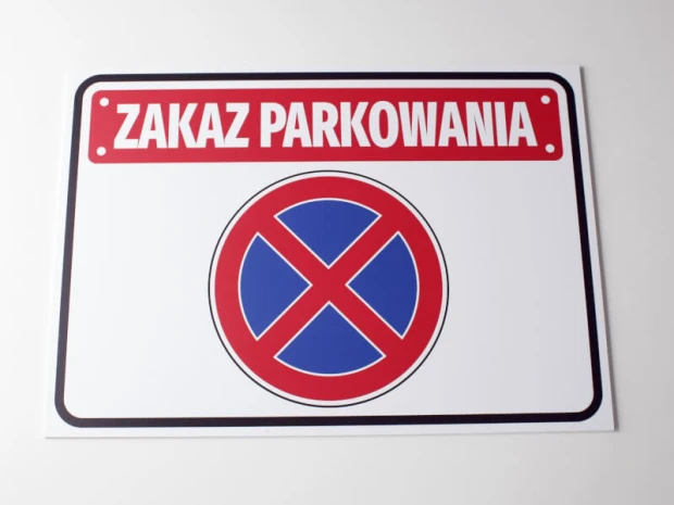 Tabliczka Zakaz parkowania T039 - Wzór graficzny. Prostokątna tabliczka z czerwonym napisem na białym tle oraz niebieskim
