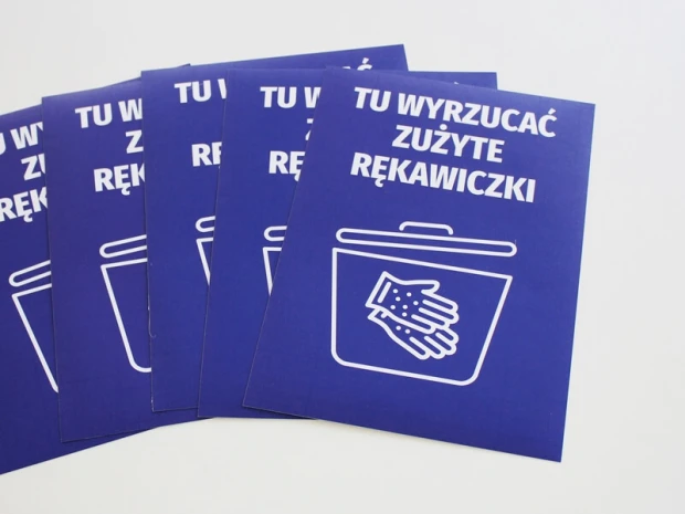 Zestaw niebieskich naklejek BHP z napisem Tu wyrzucać zużyte rękawiczki i piktogramem kosza, ułożonych w wachlarz