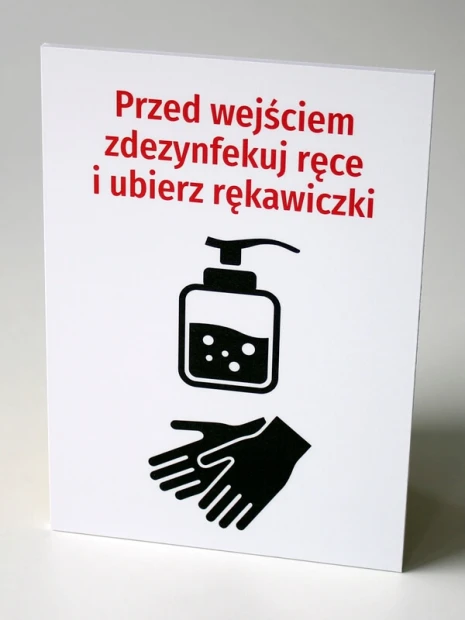 Tabliczka Przed wejściem zdezynfekuj ręce i ubierz rękawiczki - Wzór graficzny. Biała tabliczka z czerwoną czcionką