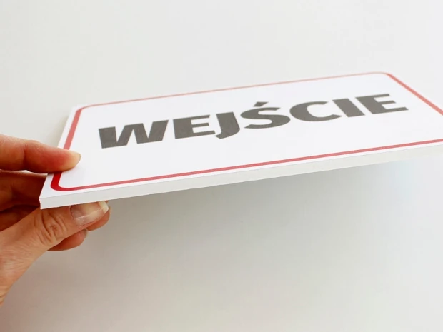 Tabliczka informacyjna z napisem WEJŚCIE w ujęciu pokazującym grubość i strukturę materiału płyty