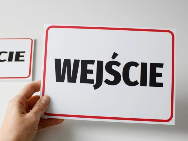 Tabliczka informacyjna z napisem WEJŚCIE w czerwonej ramce, trzymana w dłoni dla pokazania skali produktu