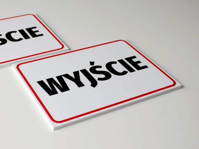 Tabliczka wyjście T047 - Wzór graficzny. Prosta forma prostokątna z białym tłem i dużym czarnym napisem. Czerwony kontur