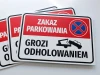 Tabliczka Zakaz parkowania, grozi odholowaniem - Wzór graficzny. Prostokątna tabliczka z czerwonym tłem, białym napisem