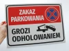 Tabliczka Zakaz parkowania, grozi odholowaniem - Wzór graficzny. Czerwone tło z białym napisem i symbolem odholowania