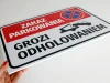 Tabliczka Zakaz parkowania, grozi odholowaniem - Wzór graficzny. Prostokątna tabliczka z czerwonym tłem, białym napisem