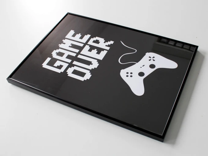 Plakat game over 001 - Wzór graficzny. Na czarnym tle białe napisy GAME OVER oraz kontroler w stylu pikselowym