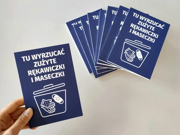Niebieskie tabliczki BHP Tu wyrzucać zużyte rękawiczki i maseczki w dłoni oraz ułożone w wachlarz