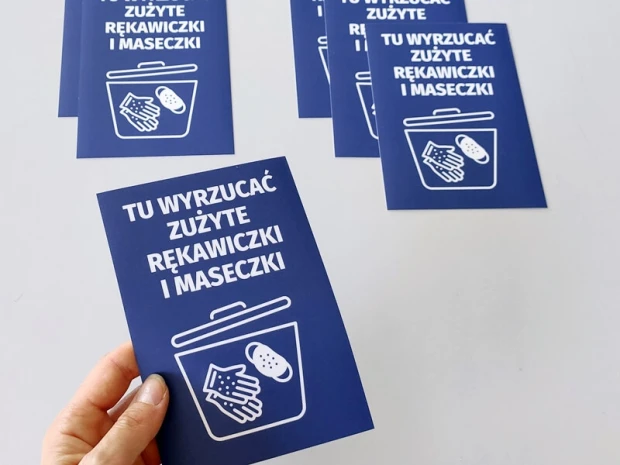 Naklejka Tu wyrzucać zużyte rękawiczki i maseczki - Wzór graficzny. Grafika przedstawia kosz na śmieci z dłońmi