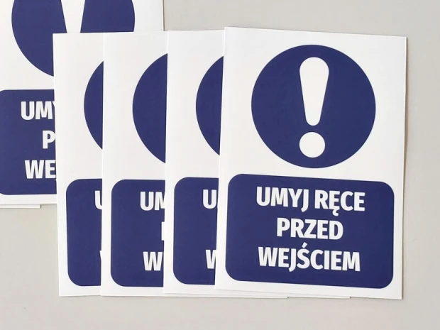 Niebieskie naklejki nakazu BHP z wykrzyknikiem i napisem Umyj ręce przed wejściem, ułożone schodkowo