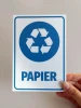Tabliczka na kosz Papier - Wzór graficzny. Okrągły symbol recyklingu z niebieskimi strzałkami i napisem Papier