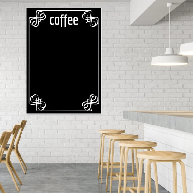 Czarna tablica kredowa z białym nadrukiem napisu coffee oraz ozdobną ramką we wnętrzu kawiarni