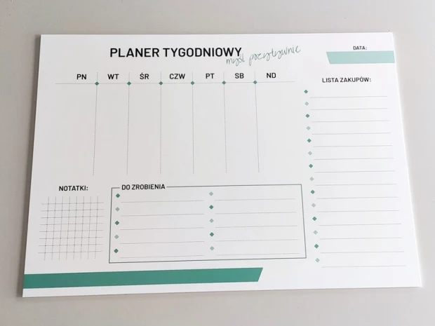 Tablica suchościeralna z nadrukiem planera tygodniowego i przykładowym odręcznym napisem na powierzchni