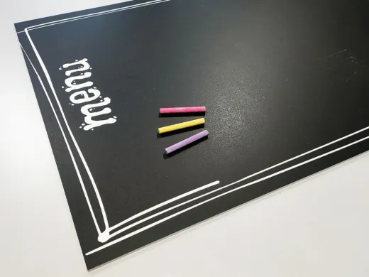 Tablica kredowa z nadrukiem menu i trzema kolorowymi kredami w ujęciu z góry